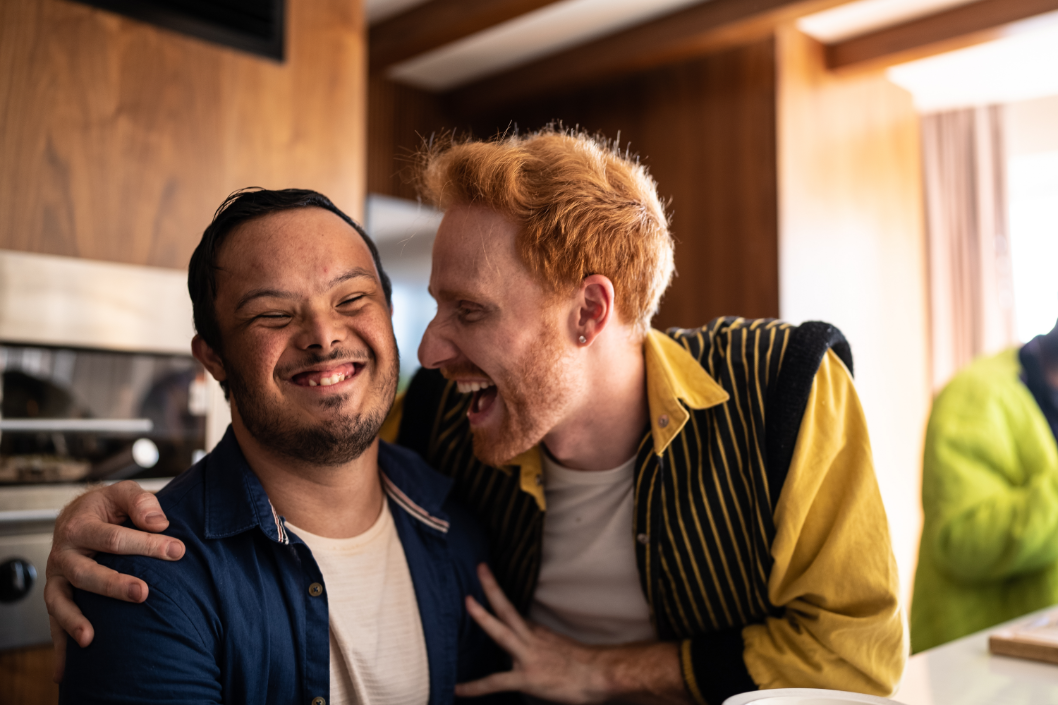 Young man with downs syndrome and friend laughing